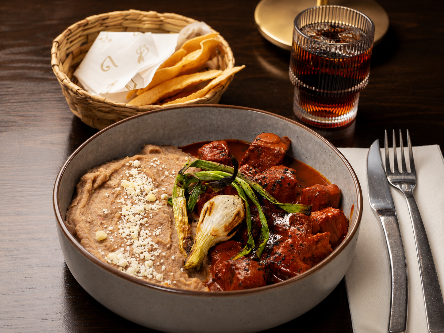 Northern Mexican stew with refried beans and grilled spring onions